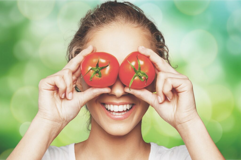Beautiful laughing woman holding two ripe tomatoes